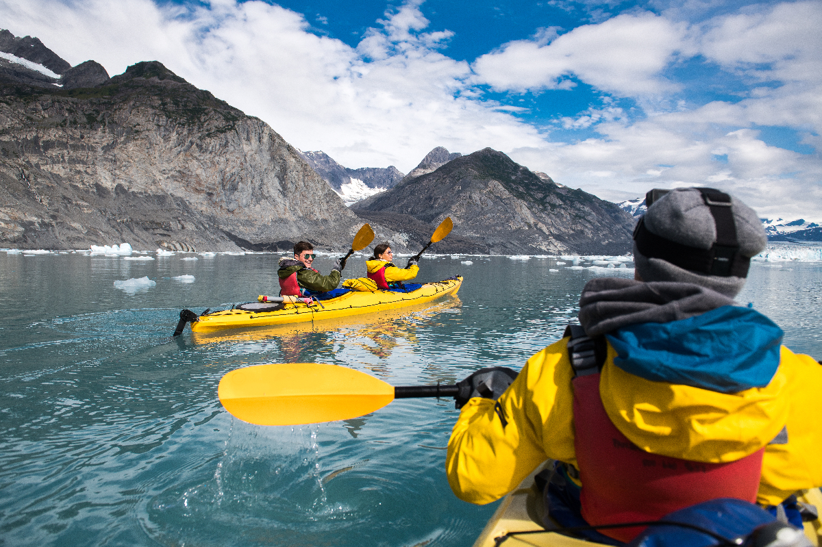 Group of friends enjoy ocean kayaking bear glacier during their vacation trip to in Alaska, USA