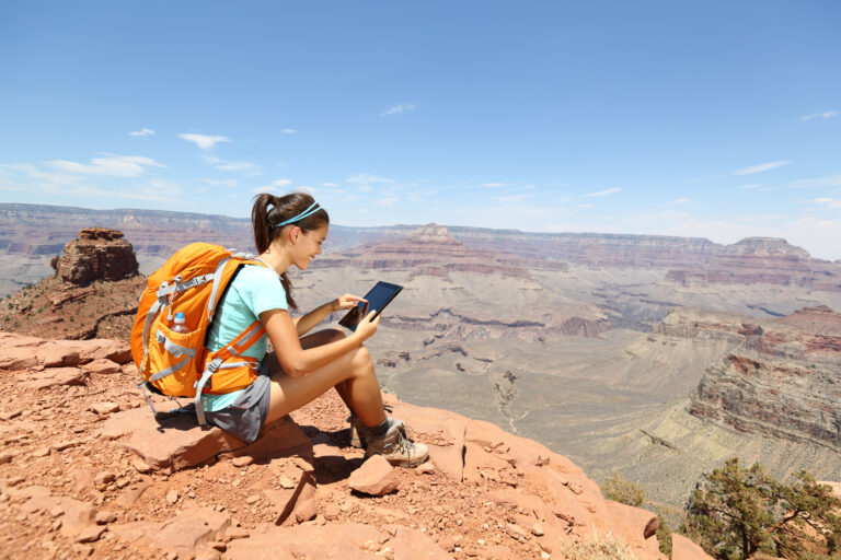 Tablet computer woman hiking in Grand Canyon using travel app or map during her hike. Multiethnic hiker girl relaxing on South Kaibab Trail, south rim of Grand Canyon, Arizona, USA.