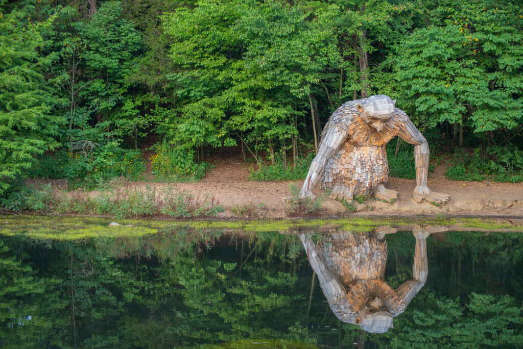 Bernheim Forest, Kentucky / United States - Aug 17, 2019: Forest Giant Little Nis reflecting on pond, Art installation by Thomas Dambo